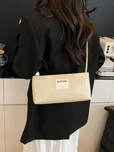 Sac baguette beige minimaliste avec écusson à lettres sur un blazer noir élégant