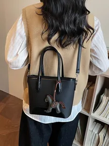 Bolso cubo de cuero negro con colgante de caballo, mostrado por modelo en interior