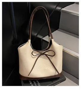 Détail du sac cabas crème avec poignées marron et décoration élégante de nœud