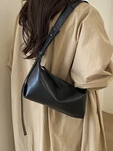 Minimalist black baguette shoulder bag in smooth leather with adjustable strap for women