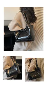 Vue détaillée du sac cabas noir brillant avec nœud décoratif et texte embossé