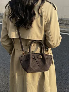 Sac seau vintage en daim marron foncé avec coutures matelassées et détails dorés sur modèle