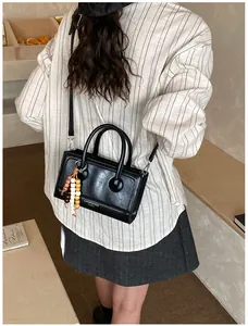 Détail du sac baguette en cuir noir avec pendentif en perles et boucles argentées
