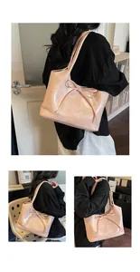 Détail d'un sac cabas rose clair avec décoration nœud et logo de la marque