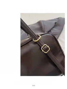 Détail macro de la boucle en métal doré sur le sac fourre-tout en cuir marron brillant