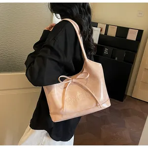Détail du sac cabas beige avec nœud papillon et texture de logo embossé