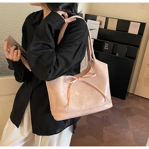Détail du sac cabas en cuir PU rose avec décoration nœud et lettrage en relief