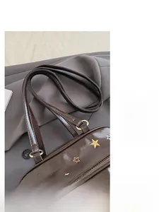 Détail d'un cabas en cuir marron avec étoiles brodées et poignées en métal doré