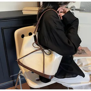Détail du sac fourre-tout crème avec bordure contrastée brune et nœud en cuir décoratif