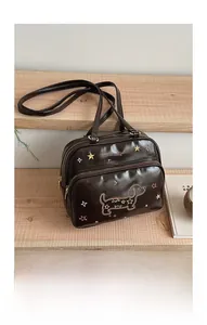 Détail de la broderie teckel sur un sac en cuir marron foncé avec double fermeture