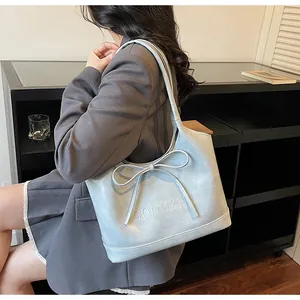 Détail du sac cabas en cuir bleu clair avec un grand nœud et lettrage GONGZHU embossé