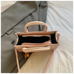 Vue intérieure du sac baguette avec compartiments et détail du pendentif à perles
