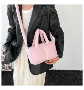 Detail of pink quilted puffer tote bag shown on model with wide adjustable shoulder strap