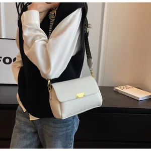 Détail d'un sac baguette blanc grainé avec une bandoulière pied-de-poule et fermoir doré