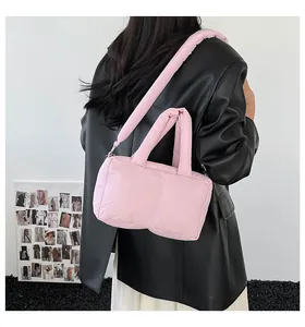 Model view of a pink quilted puffer tote bag with detachable strap and padded handles