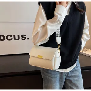 Détail de la texture cuir litchi blanc et bandoulière géométrique d'un sac baguette
