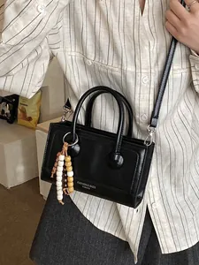Sac baguette chic noir avec breloque perlée et bandoulière pour un style élégant