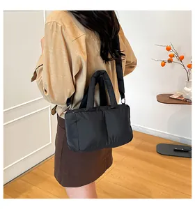 Close-up of a black quilted tote bag with dual handles and an adjustable shoulder strap