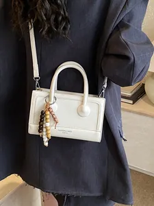Sac baguette beige chic avec breloque en perles et bandoulière réglable pour l'épaule