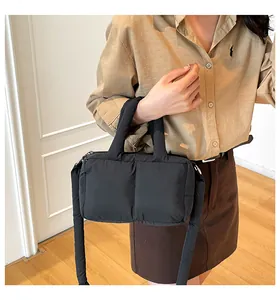 Close-up of black padded nylon tote bag worn crossbody with a minimalist aesthetic