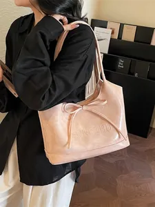 Sac fourre-tout rose en cuir avec nœud et bandoulière présenté dans un cadre élégant