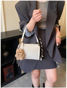 Vue détaillée d'un sac à main blanc en cuir avec pendentif ours et boucles dorées