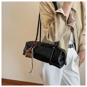 Detail of black wax leather tote bag featuring wrinkled texture and decorative mini pendant