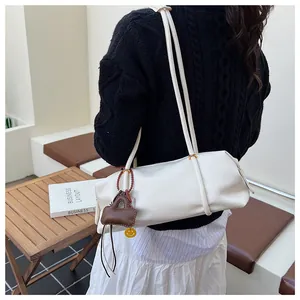 Detail of white lychee leather texture on a chic baguette bag with a yellow smiley charm