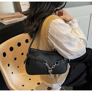 Detail of black lychee texture leather underarm bag with silver chain and heart pendant