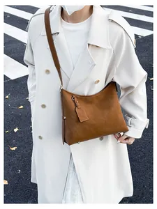 Detailed view of brown suede tote bag featuring protective metal bottom studs and matte finish