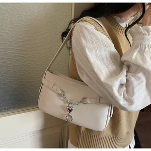 Detail showing white litchi grain shoulder bag with silver heart chain accessory