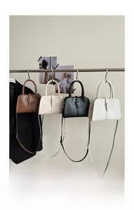 Detail view of four minimalist square handbags in neutral colors hanging on a rack