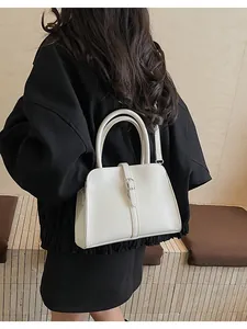 Detail view of cream leather handbag showing top handles and adjustable shoulder strap