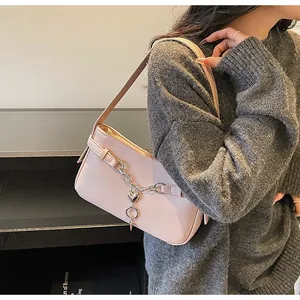 Detail view of light pink baguette bag featuring a silver heart charm and metal chain