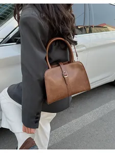 Brown leather handbag shown in a lifestyle scene with a model and a white car