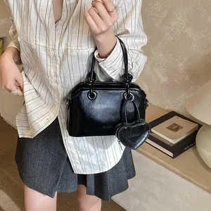 Minimalist black shell handbag with a heart-shaped charm and double top handles