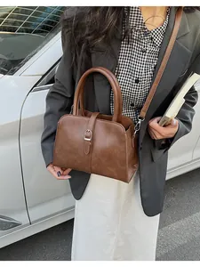 Detail view of a vintage brown leather crossbody bag with metallic buckle and carry handle