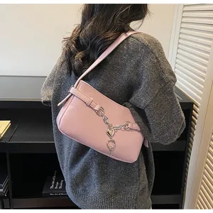 Detail view of pink baguette bag with silver heart chain accessory on shoulder