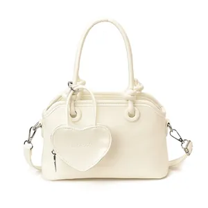 Minimalist cream shell handbag with top handle and matching heart-shaped coin purse charm
