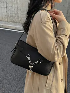 Retro black leather baguette bag with silver heart chain, worn over the shoulder