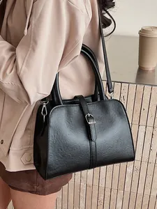 Minimalist black pebble leather tote bag with crossbody strap shown on a model