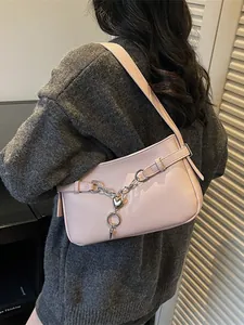 Pink PU leather baguette bag with silver chain and heart charms shown on shoulder