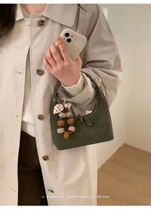 Detail der dunkelgrünen Retro-Handtasche mit Plüsch-Anhänger und beigem Trenchcoat