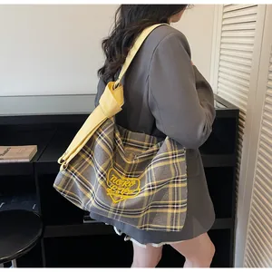 Detail of checkered tote bag with yellow heart embroidery and stylish knotted strap