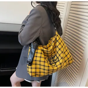 Detail of yellow plaid canvas tote with black heart embroidery and wide leather strap