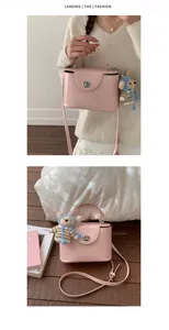 Detail view of pink square handbag featuring a metal turn-lock and cute bear charm