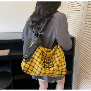 Detailed view of yellow plaid tote bag with heart embroidery and black leather straps