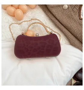 Détail du sac de soirée bordeaux avec texture animale, anse dorée et fermoir diamant