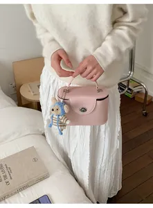Close-up of a pink leather box bag featuring a silver twist lock and cute bear charm