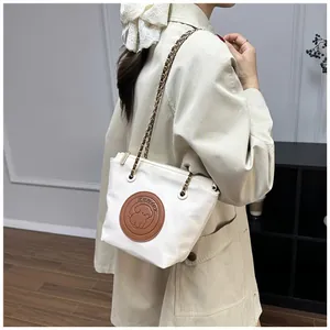 Détail du sac cabas blanc cassé avec patch chien et bandoulière chaîne sur le mannequin